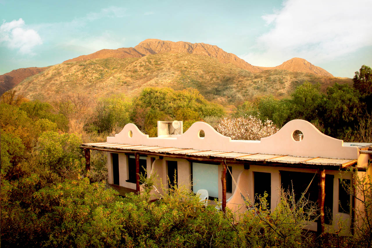 Casa de adobe de El Quebrachal del Monte con las sierras detrás